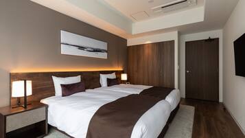 Une chambre d’hôtel moderne avec un grand lit, une table de chevet avec une lampe, un téléviseur fixé au mur et une porte.