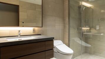 A modern bathroom with a large mirror, a sink, a toilet, and a glass-enclosed shower area.