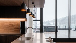 A modern kitchen with a long island, pendant lights, and a view of the outdoors. - The Vale Rusutsu (Rusutsu)