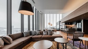 A modern living area with a large sectional sofa, round coffee tables, and a city view through large windows. - The Vale Rusutsu (Rusutsu)