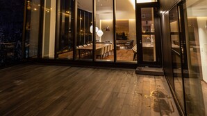 A modern building with large glass doors leading to an interior dining area with a wooden table and chairs. - The Vale Rusutsu (Rusutsu)
