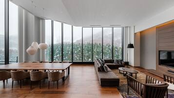 Amplia sala de estar con una gran mesa de comedor de madera, asientos cómodos, un sofá y un televisor.
