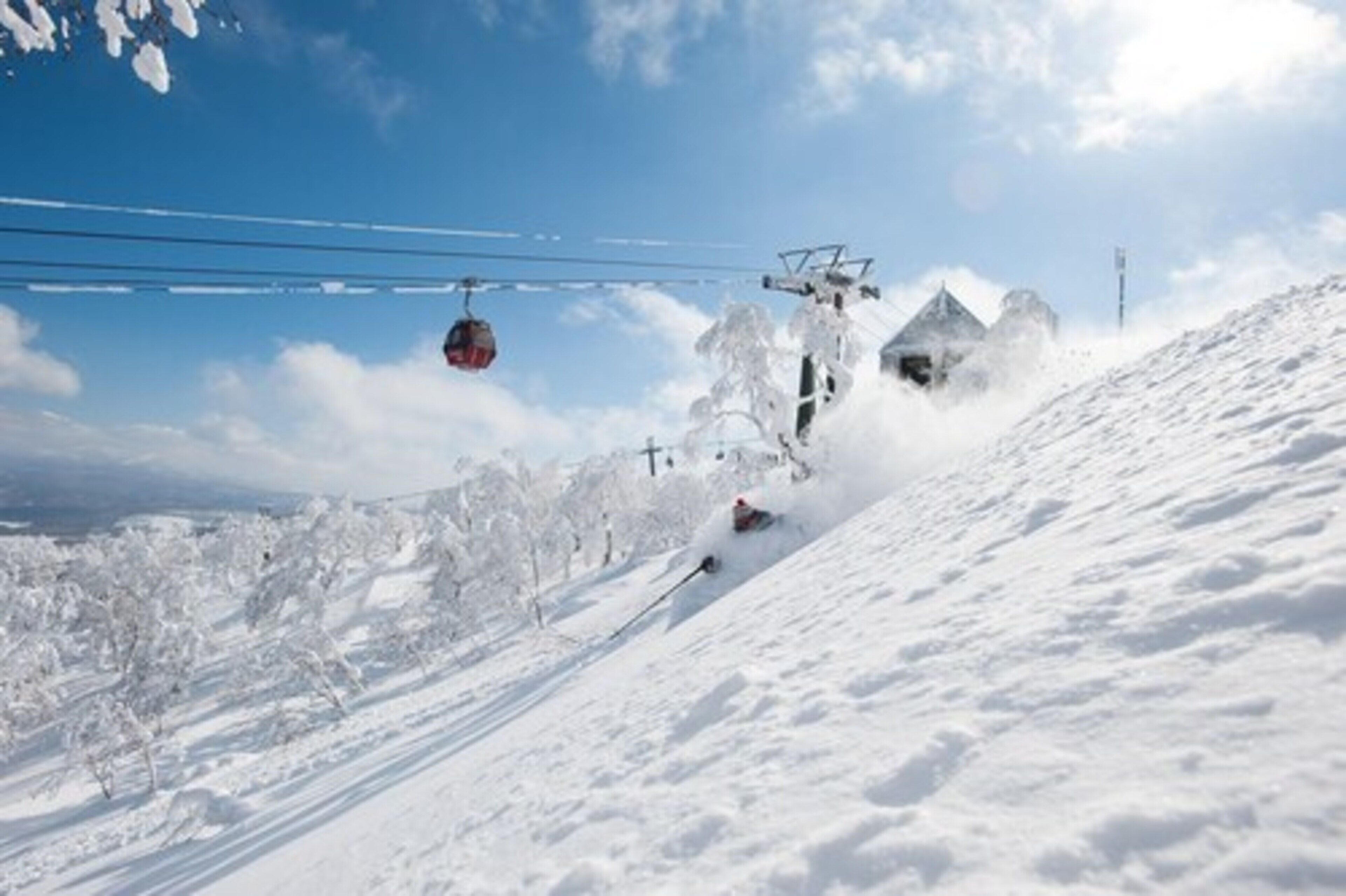 Une piste de ski avec un télésiège et une personne qui descend la piste en skiant.