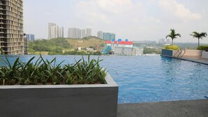 A rooftop pool with a view of high-rise buildings and a hill in the background. - Happy Home Inn Sdn Bhd (Iskandar Puteri)