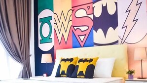 A modern bedroom with a colorful wall mural, a yellow bed, and a bedside table with a lamp. - Happy Home Inn Sdn Bhd (Iskandar Puteri)