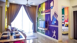 A modern hotel room with a dining area, a large window with curtains, a ceiling fan, and a colorful mural on the wall. - Happy Home Inn Sdn Bhd (Iskandar Puteri)