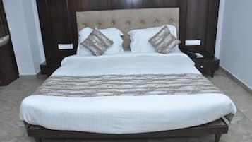A neatly made bed with a wooden headboard, two nightstands with a phone and a book, and a marble-patterned bedspread.