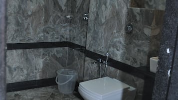 A bathroom with a marble wall, a bathtub, a shower, and a toilet.