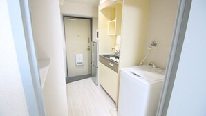 A narrow hallway leading to a small kitchenette with a refrigerator, a microwave, and a sink. - Narimasu Apartment 33 (Tokyo)