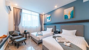 A hotel room with two beds, a sofa, a small table, and a wall-mounted air conditioner. - Begonia Resort (Panglao)