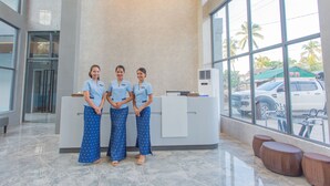 A reception desk with three staff members standing in front. - Begonia Resort (Panglao)