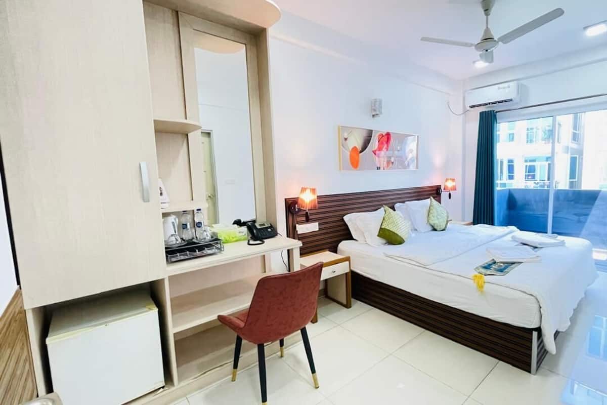A hotel room with a bed, desk, chair, and a view of the outside.