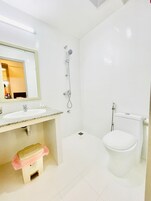 Un baño moderno con lavabo, espejo, ducha e inodoro.
