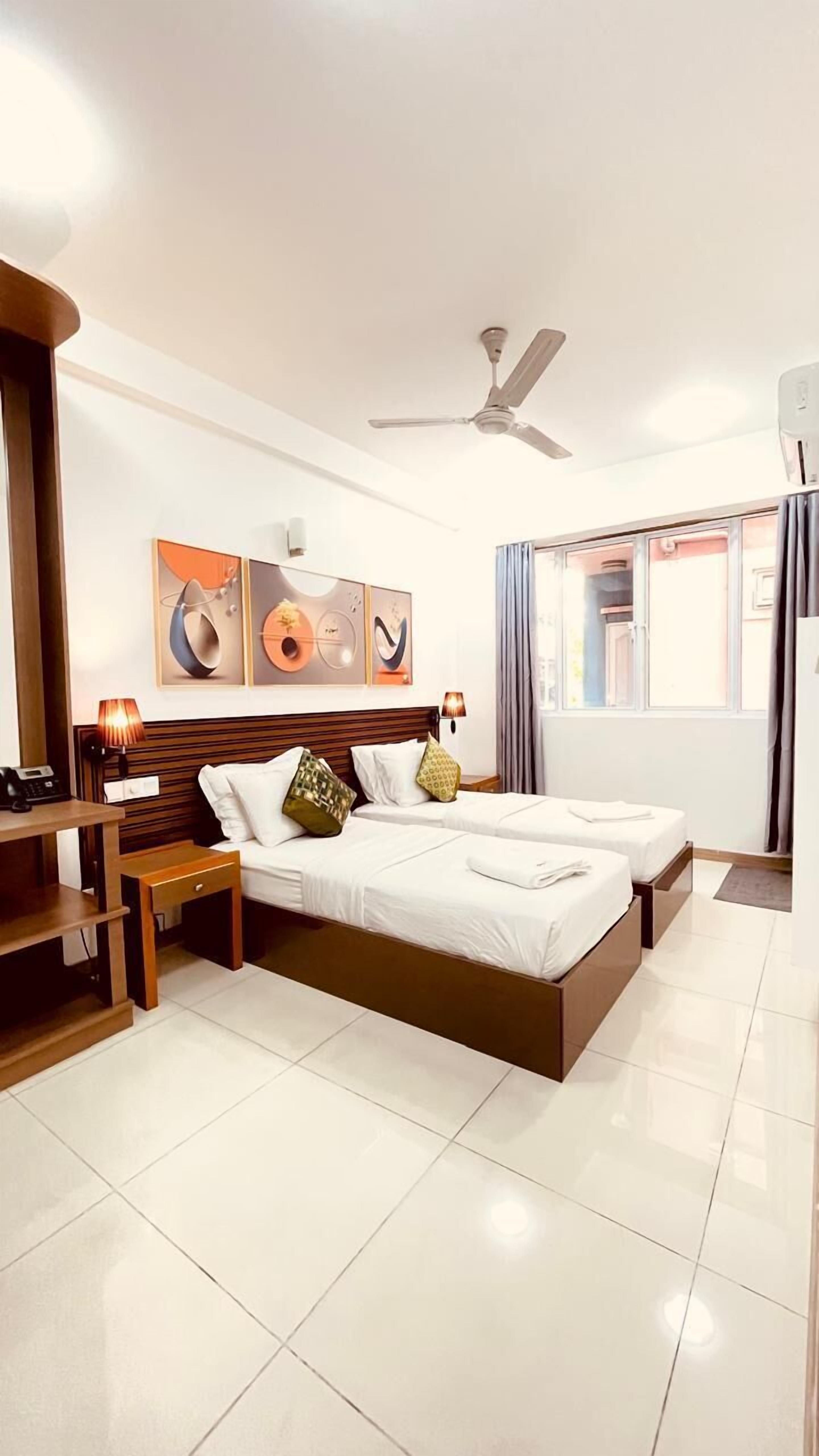Habitación de hotel moderna con una cama grande, mesitas de noche, un escritorio y un ventilador de techo.