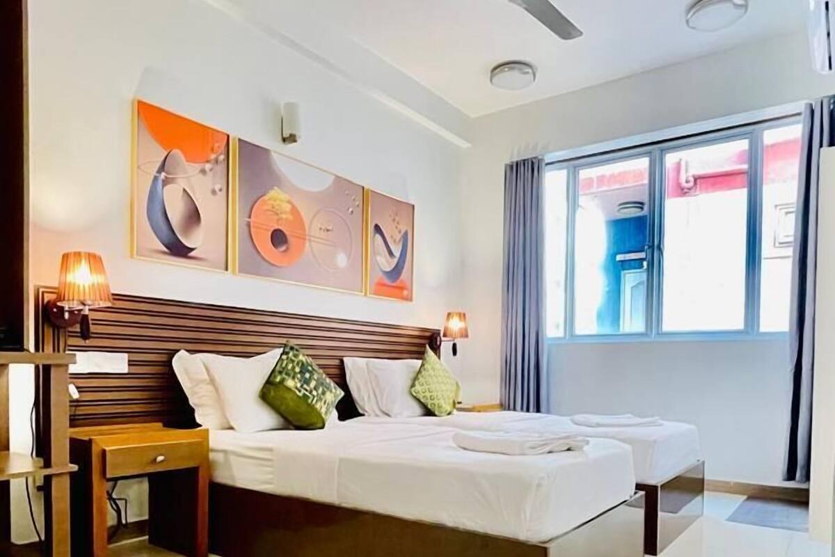 A modern hotel room with a large bed, a ceiling fan, and artwork on the walls.