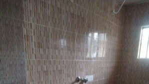 A bathroom with a tiled floor, a sink, a toilet, and a shower area.