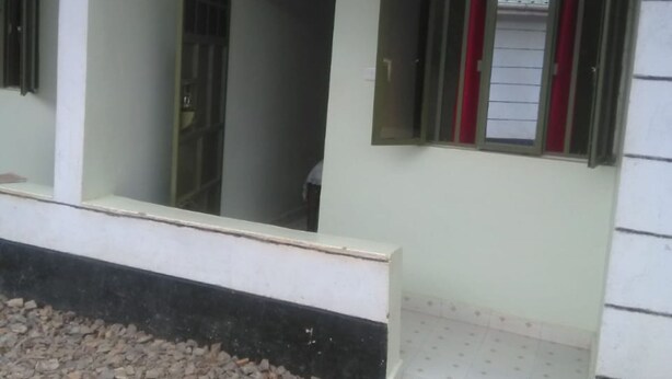 A building with a covered entrance, a tiled floor, and a gravel area in front.
