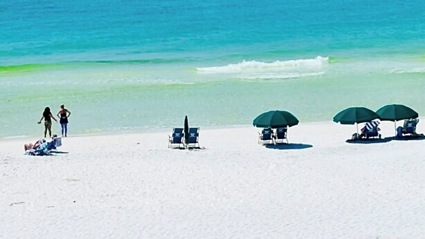 A beach with white sand, a clear blue sea, and several green umbrellas providing shade. - FlipFlopsOn II • 80 Steps to the Beach • FL 30A • Gulf Coast (Inlet Beach)