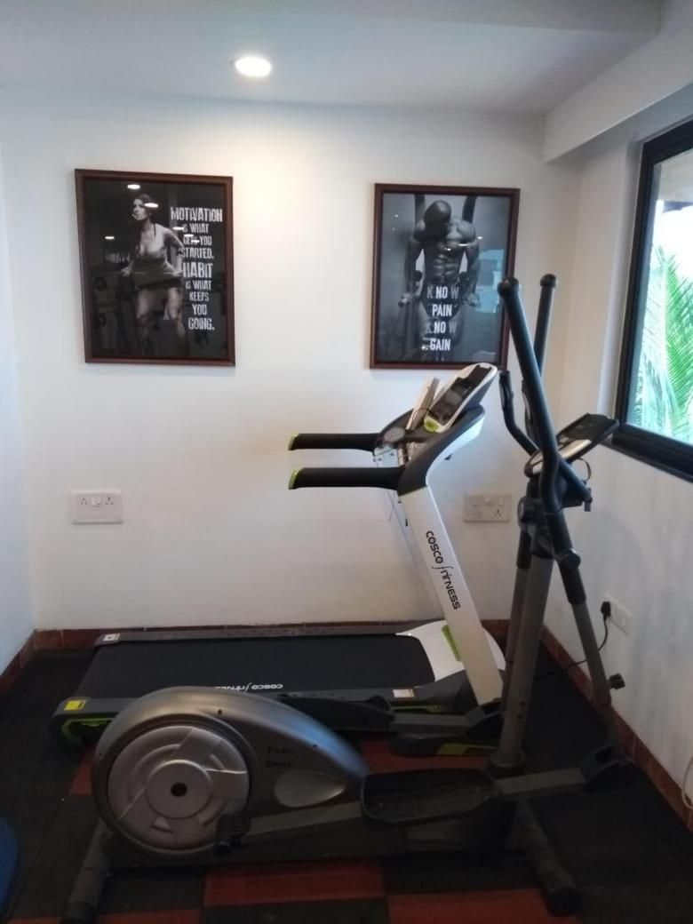 A home gym with a stationary bike, treadmill, and weight bench.