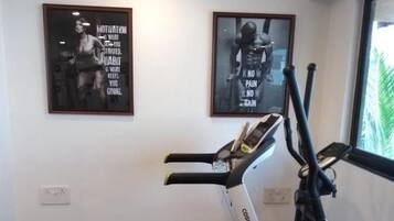 A home gym with a stationary bike, treadmill, and weight bench.
