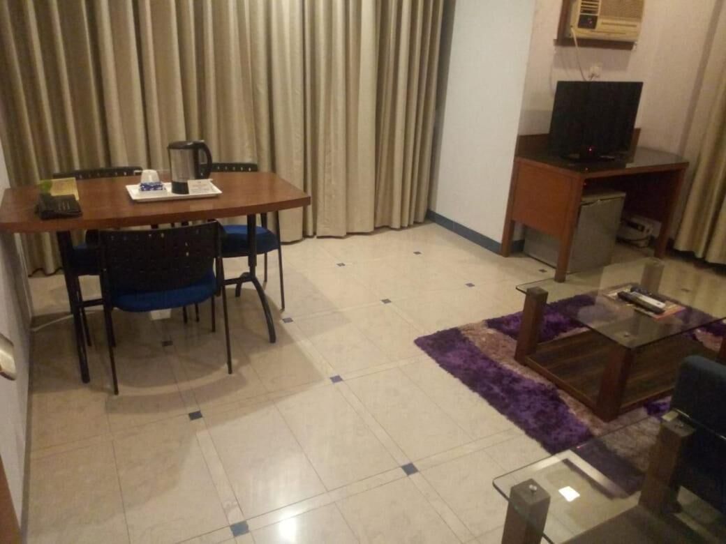 Un espacio habitable compacto con una mesa de comedor, sillas, una cafetera, un televisor y un sofá pequeño.