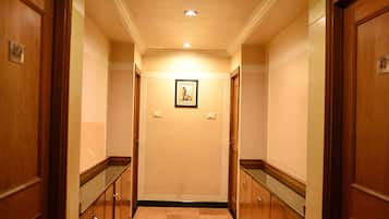 Un pasillo con puertas de madera, un cuadro enmarcado en la pared y una lámpara en el techo.