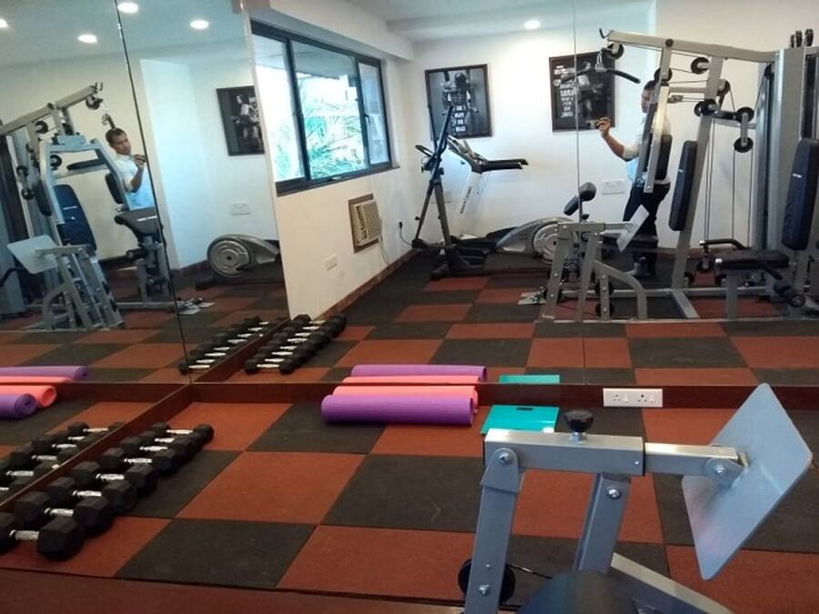 A gym with various exercise equipment, mirrors, and dumbbells.