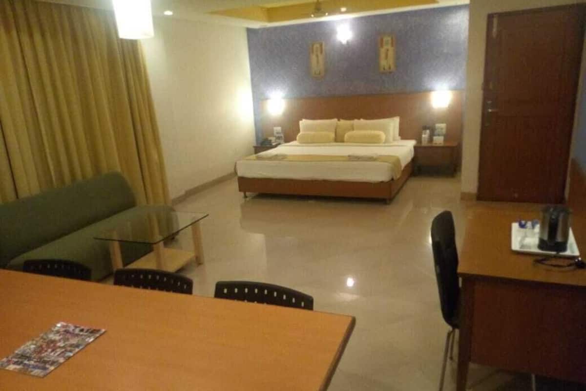 A hotel room with a bed, a desk, a chair, a table, and a couch.