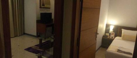 A hotel room with a bed, a desk, a chair, a television, and a wardrobe.