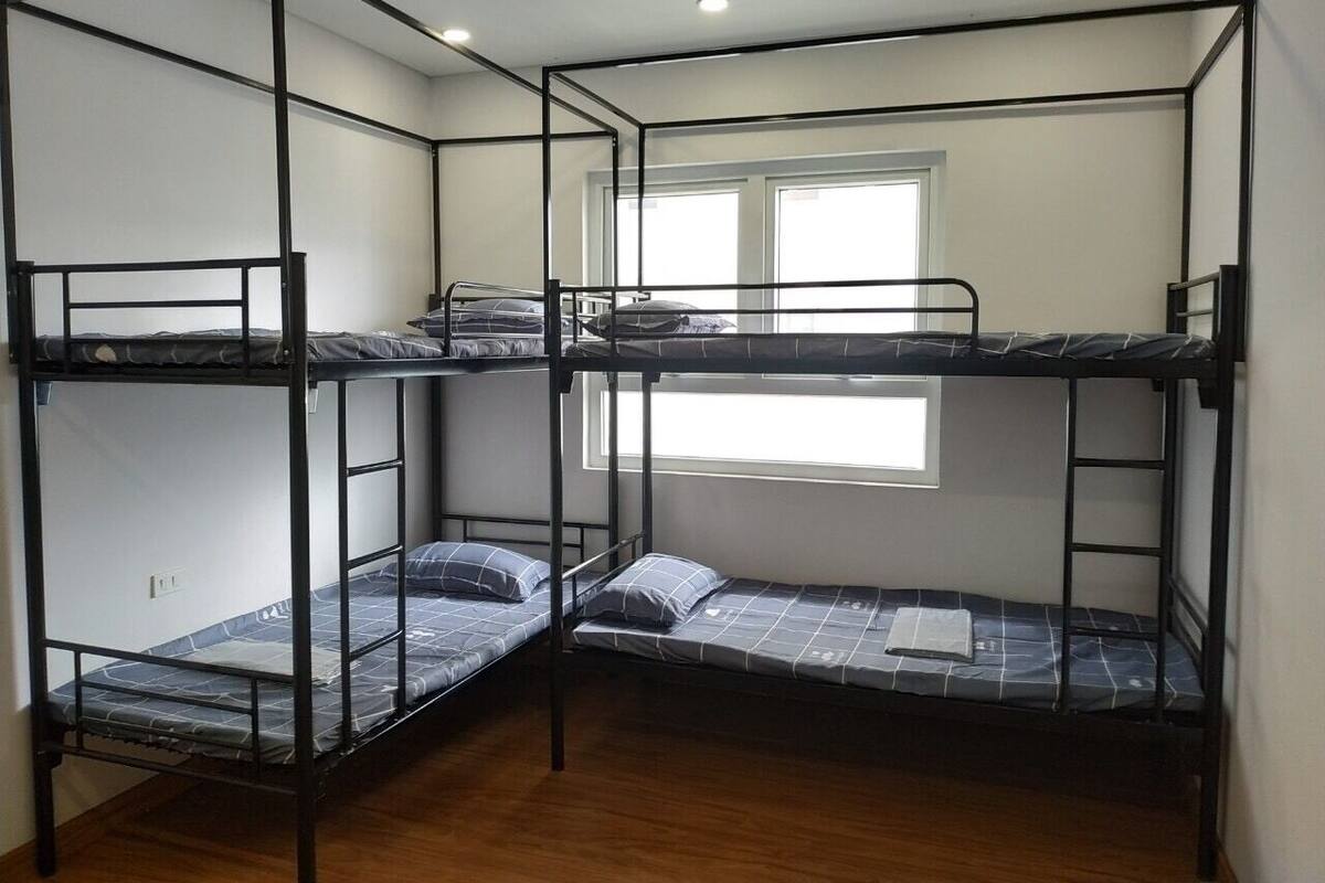 A bunk bed room with a window and wooden flooring.