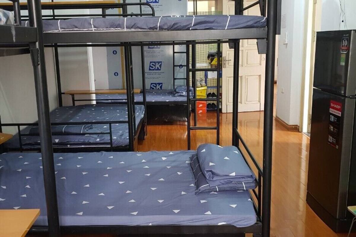 A dormitory room with bunk beds, a refrigerator, and a small table.