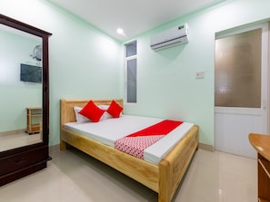A bedroom with a wooden bed, a mirror, an air conditioner, and a door with a frosted glass panel. - OYO 898 Phuong Thao Hotel (Nha Trang)