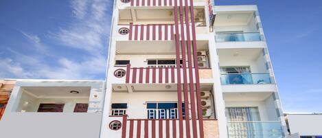 A multi-story building with a prominent vertical striped facade, a ground-level sign for 'KHÁCH SAN Phương Thảo', and balconies on the upper floors.