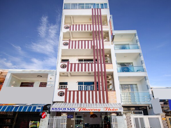 Un edificio de varios pisos con una fachada vertical a rayas llamativa, un letrero en la planta baja que dice 'KHÁCH SAN Phương Thảo' y balcones en los pisos superiores.