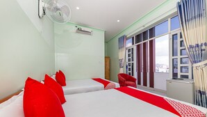 A hotel room with a large bed, a red chair, a window with curtains, and a ceiling fan. - OYO 898 Phuong Thao Hotel (Nha Trang)