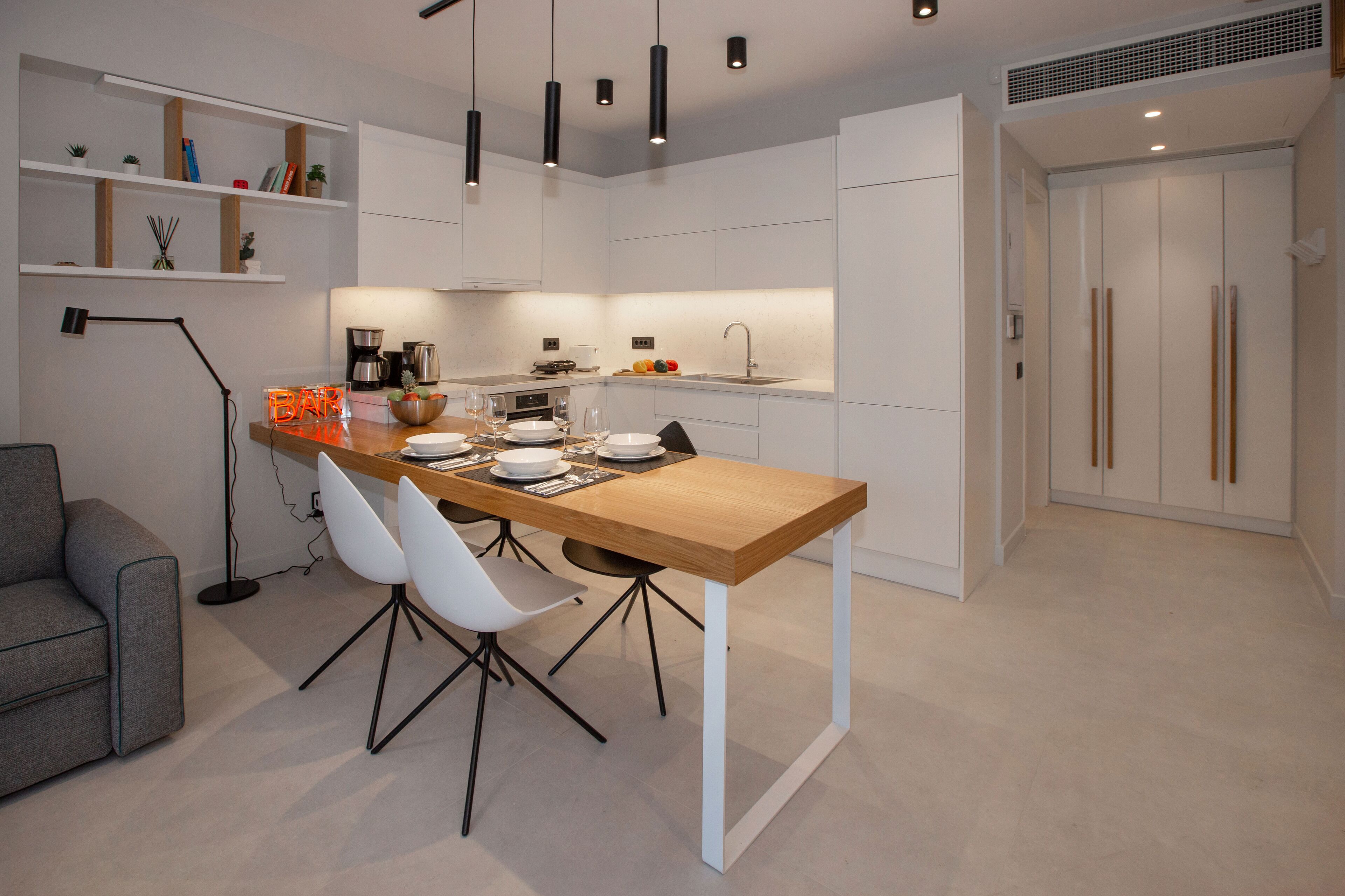 Een moderne keuken met witte kastjes, een houten eiland en zwarte hanglampen.