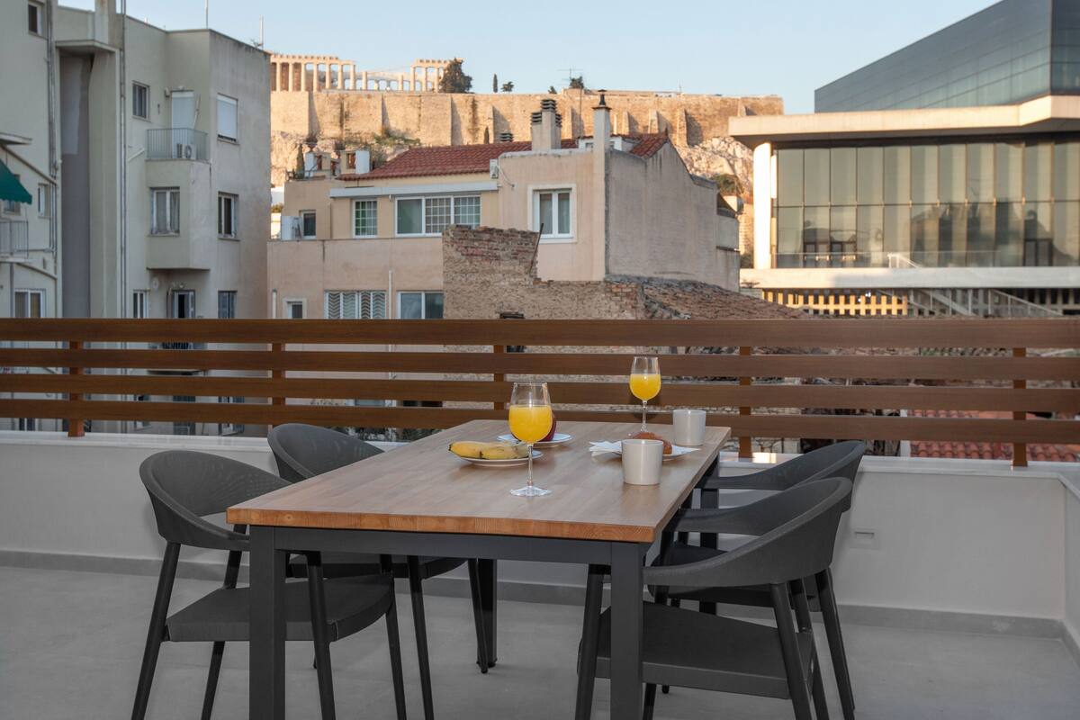 A balcony with a wooden table, two chairs, and a glass of orange juice.