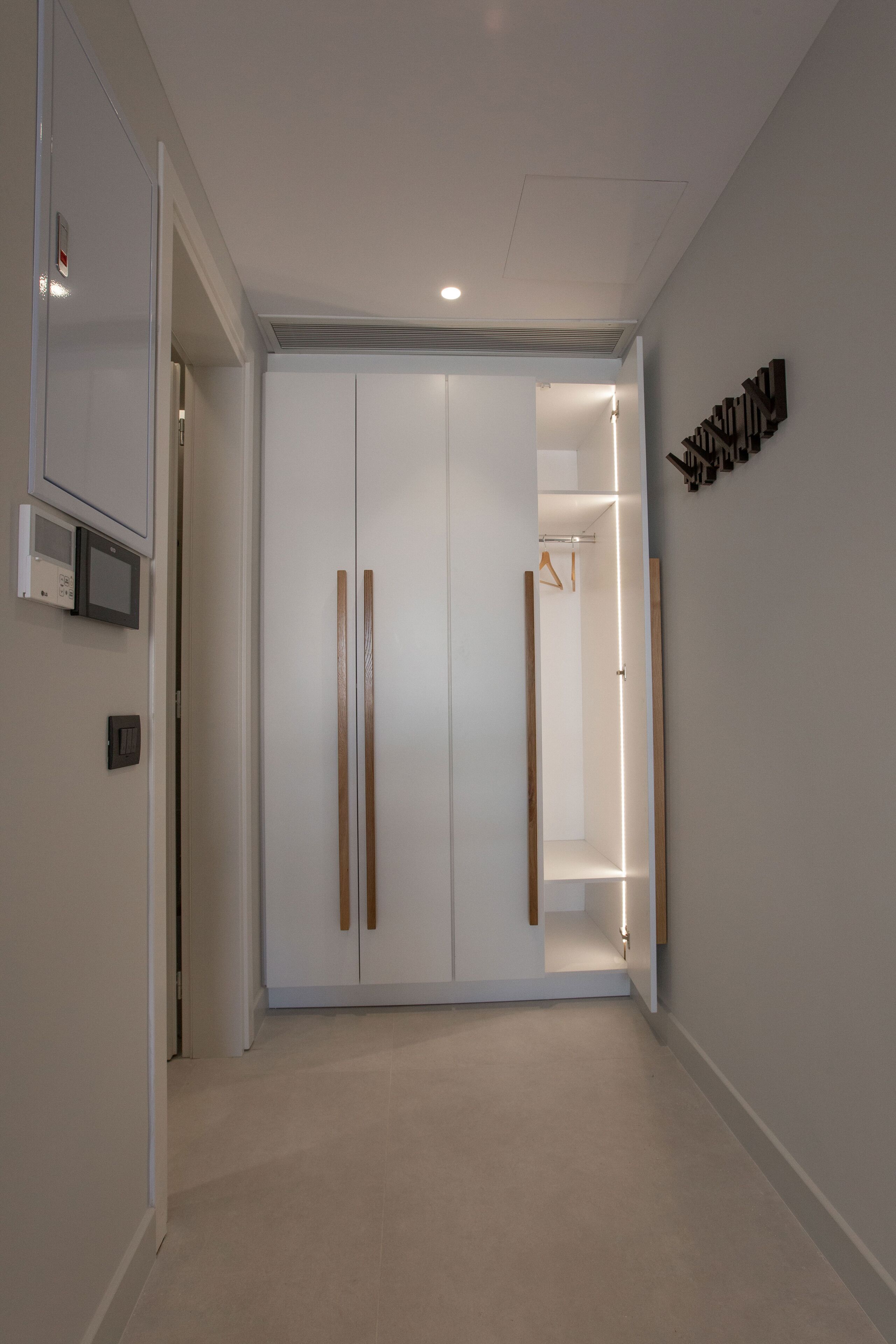 A hallway with a wardrobe, a coat rack, and a wall-mounted light fixture.