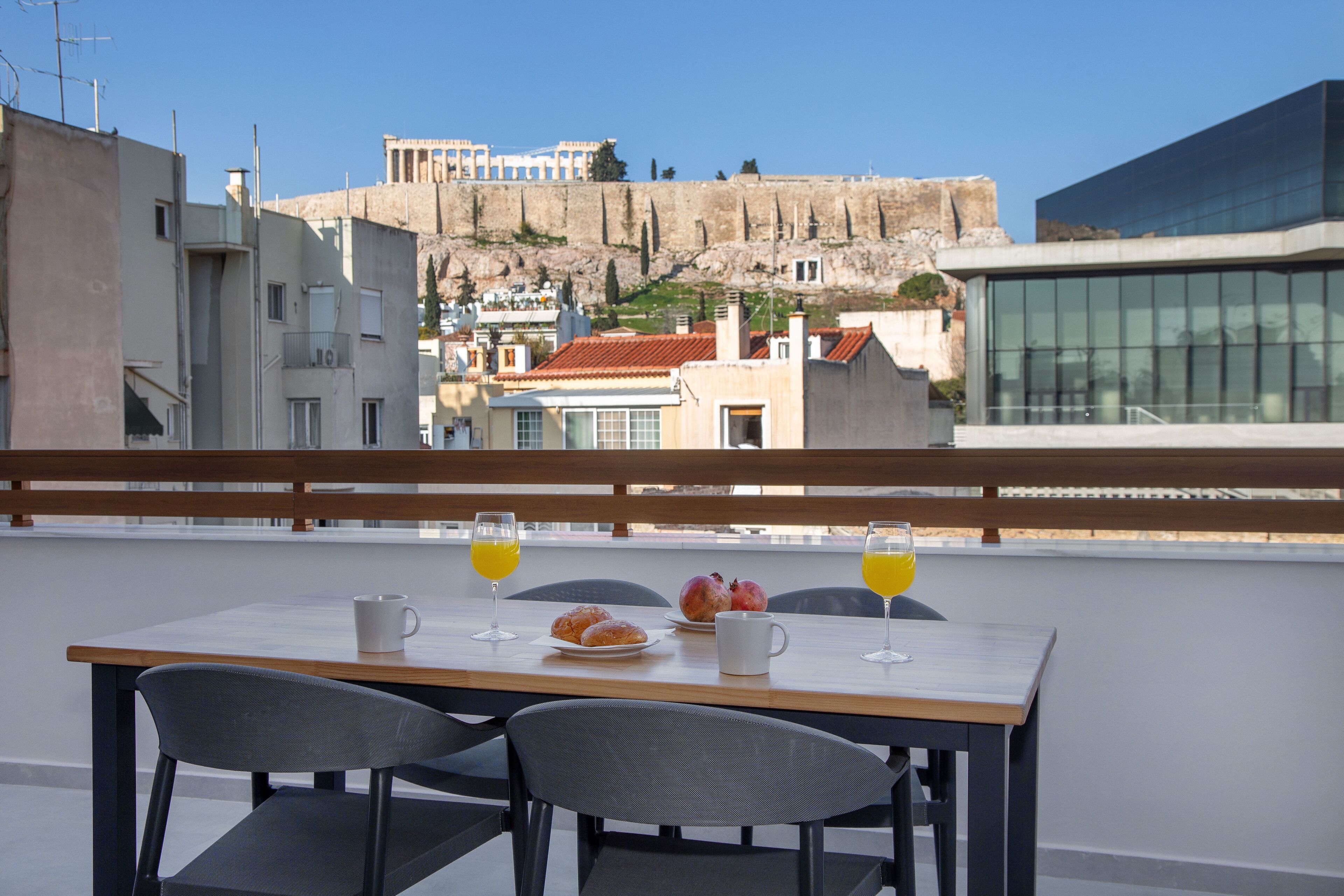 A table with breakfast items and drinks on a balcony overlooking a historic cityscape.