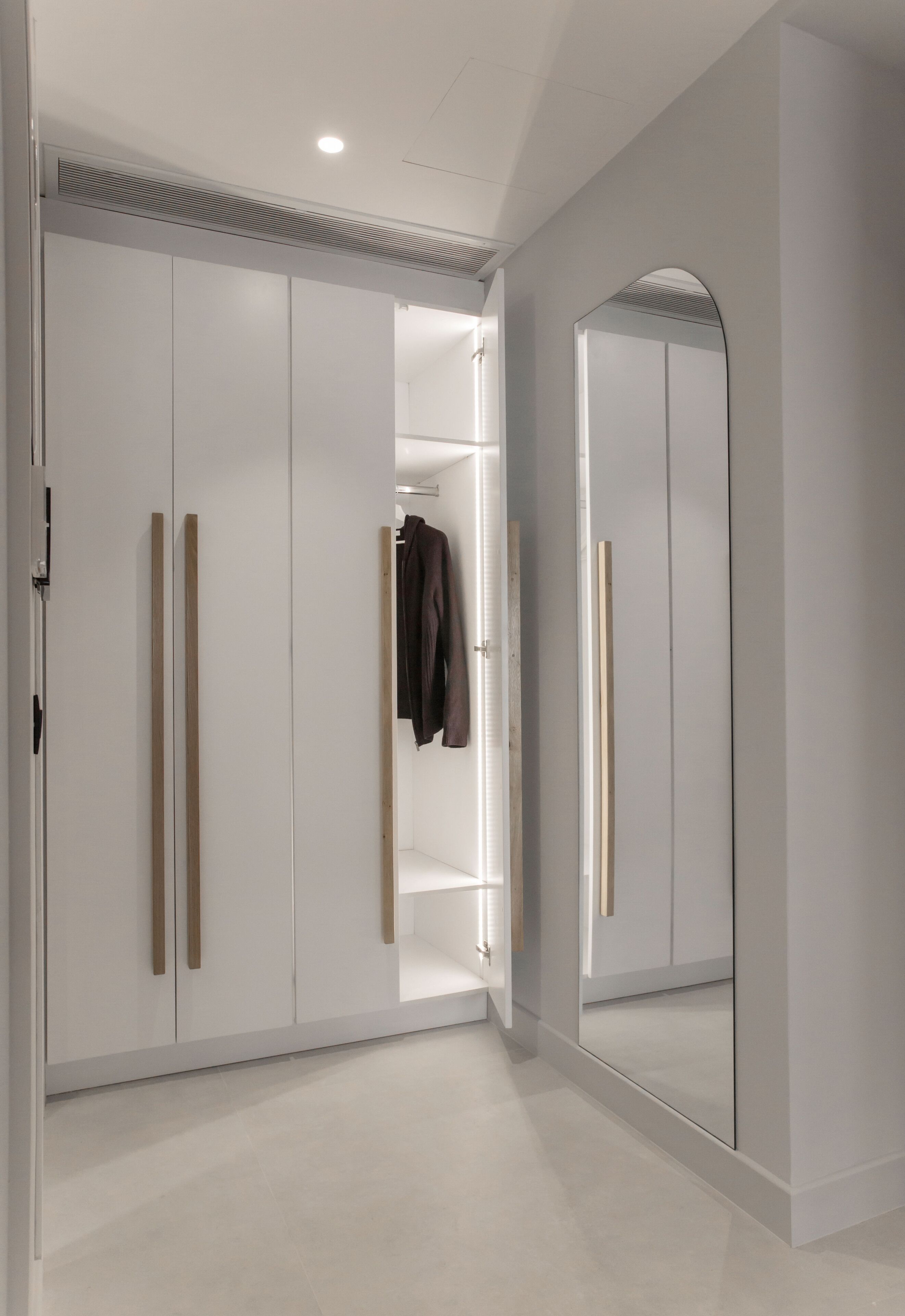 A walk-in closet with sliding doors, a mirror, and a hanging rod.