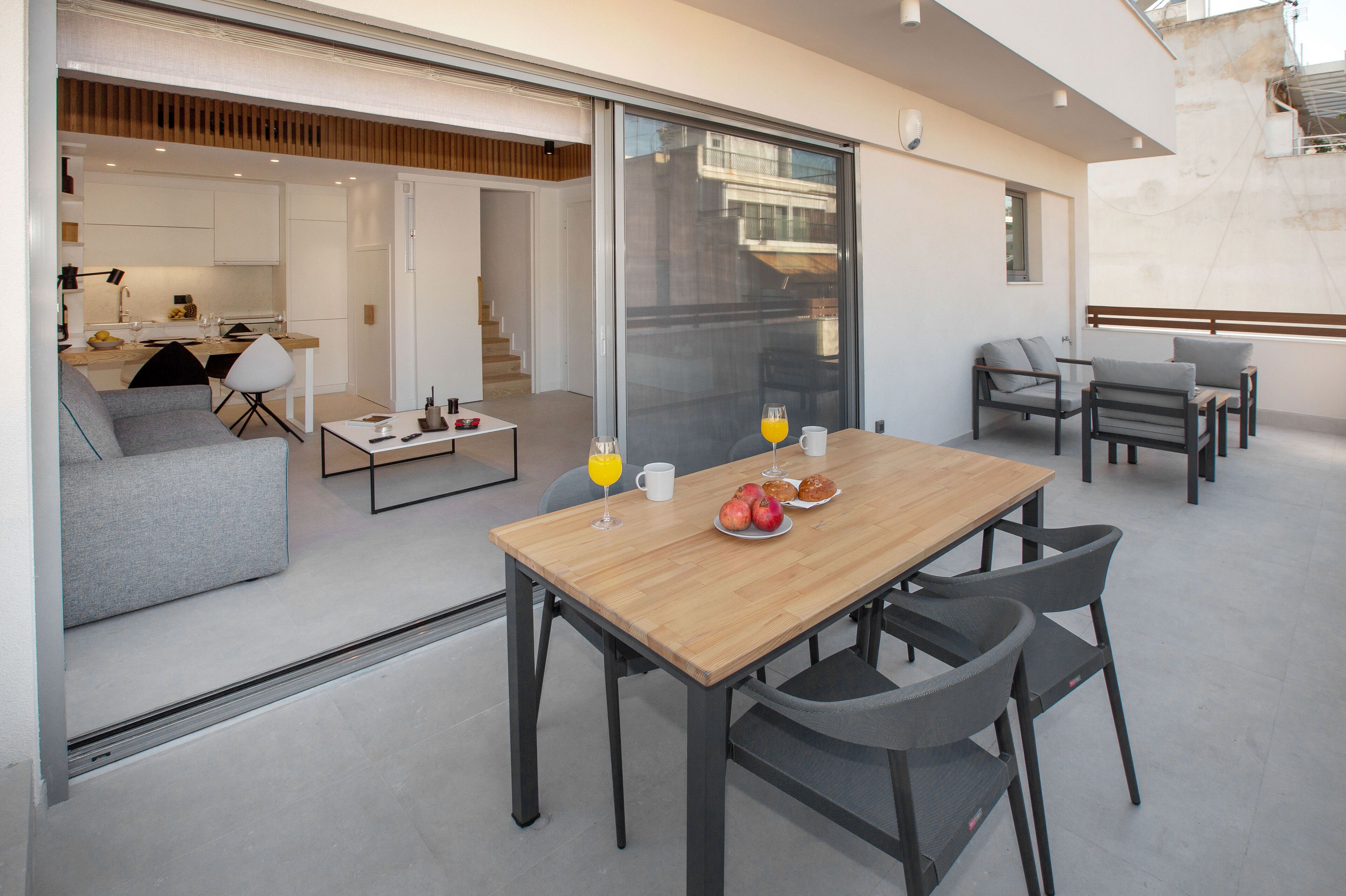 Un espace repas moderne avec une table en bois, des chaises grises et une cloison en verre.