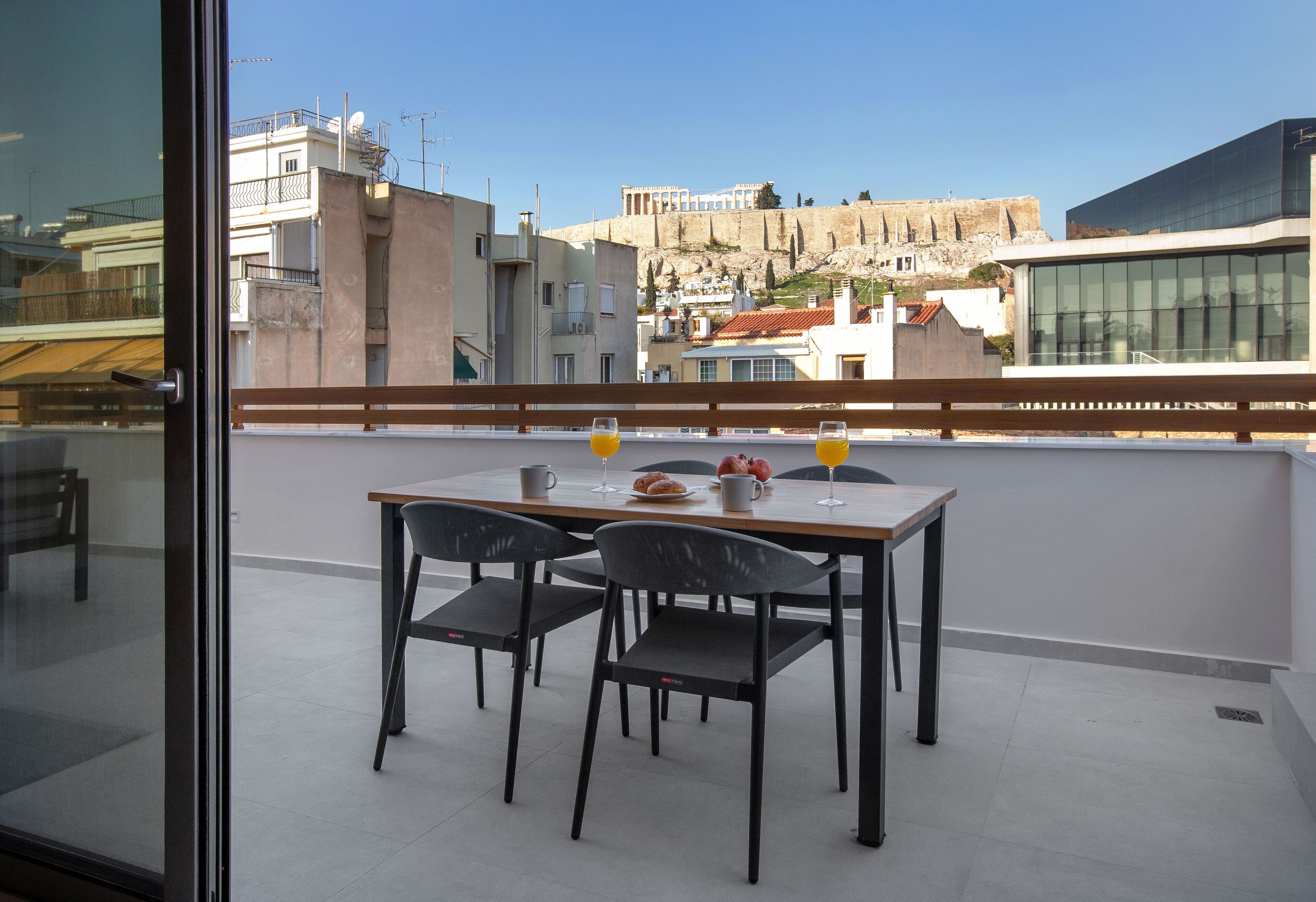 A balcony with a table and chairs, overlooking a cityscape with historical architecture.
