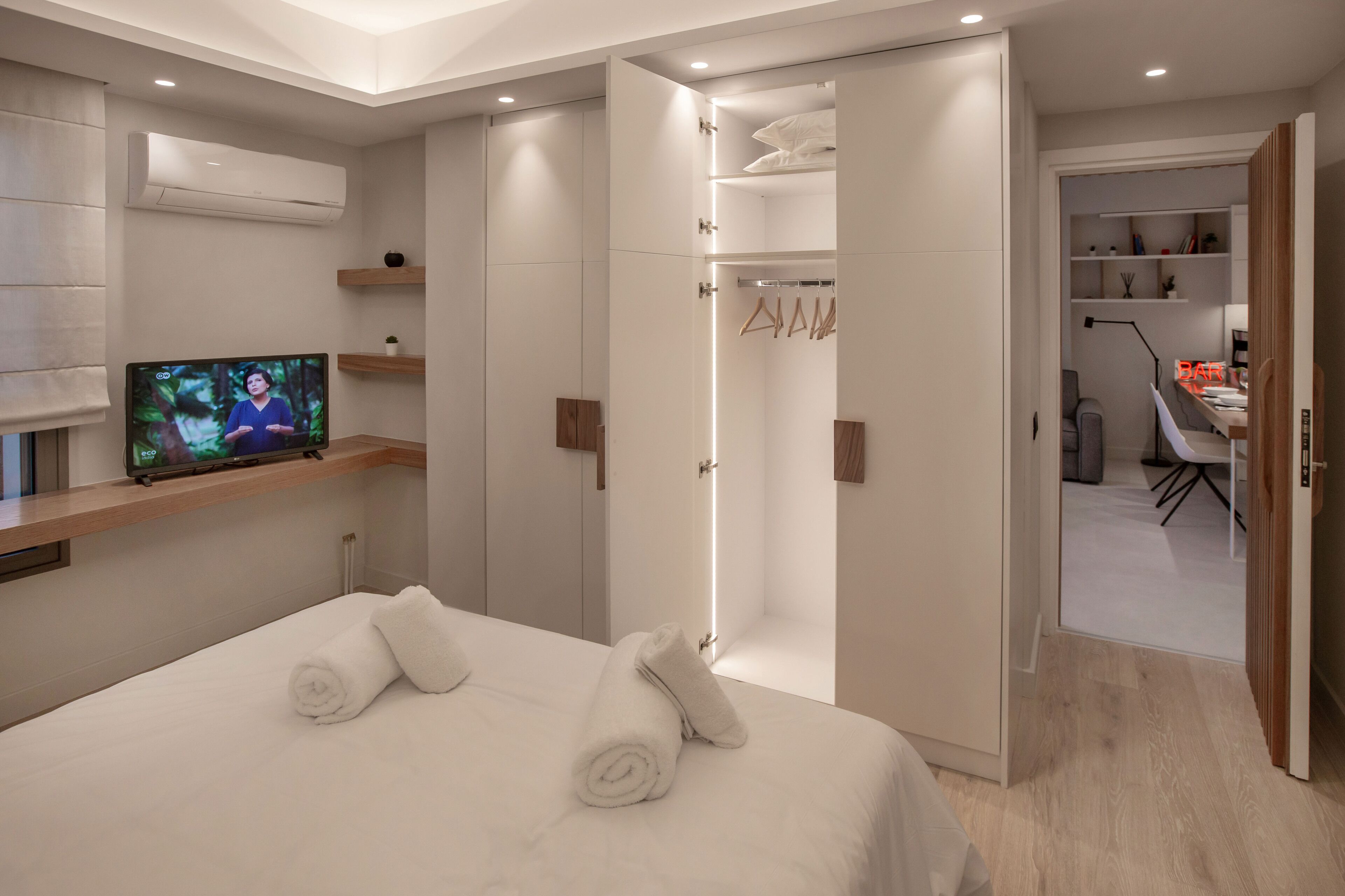 Une chambre d’hôtel moderne équipée d’un lit, d’une télévision, d’une armoire et d’un espace bureau.