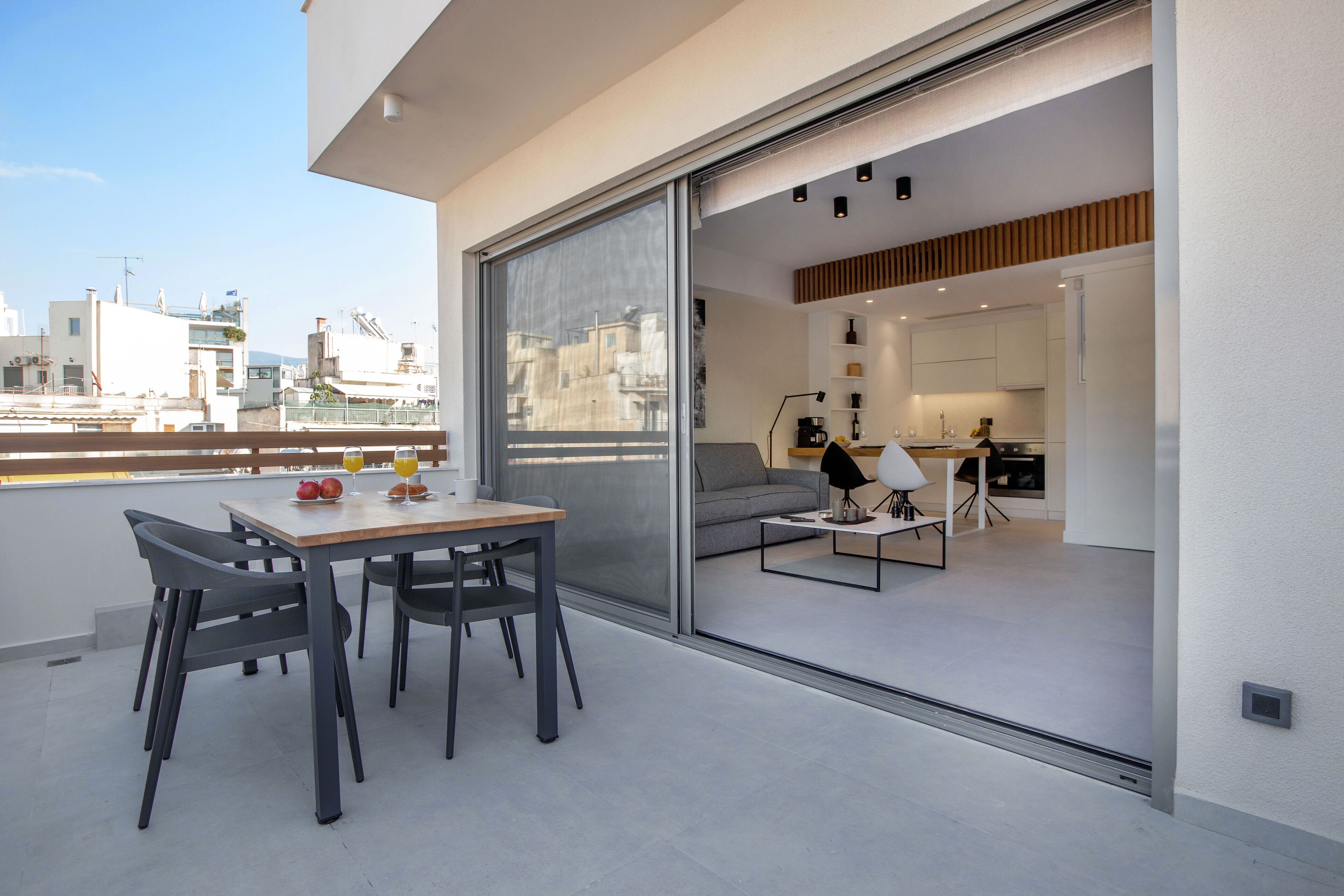 Un appartement moderne doté d’un balcon, d’un coin repas et d’une cuisine visible à travers des portes vitrées.