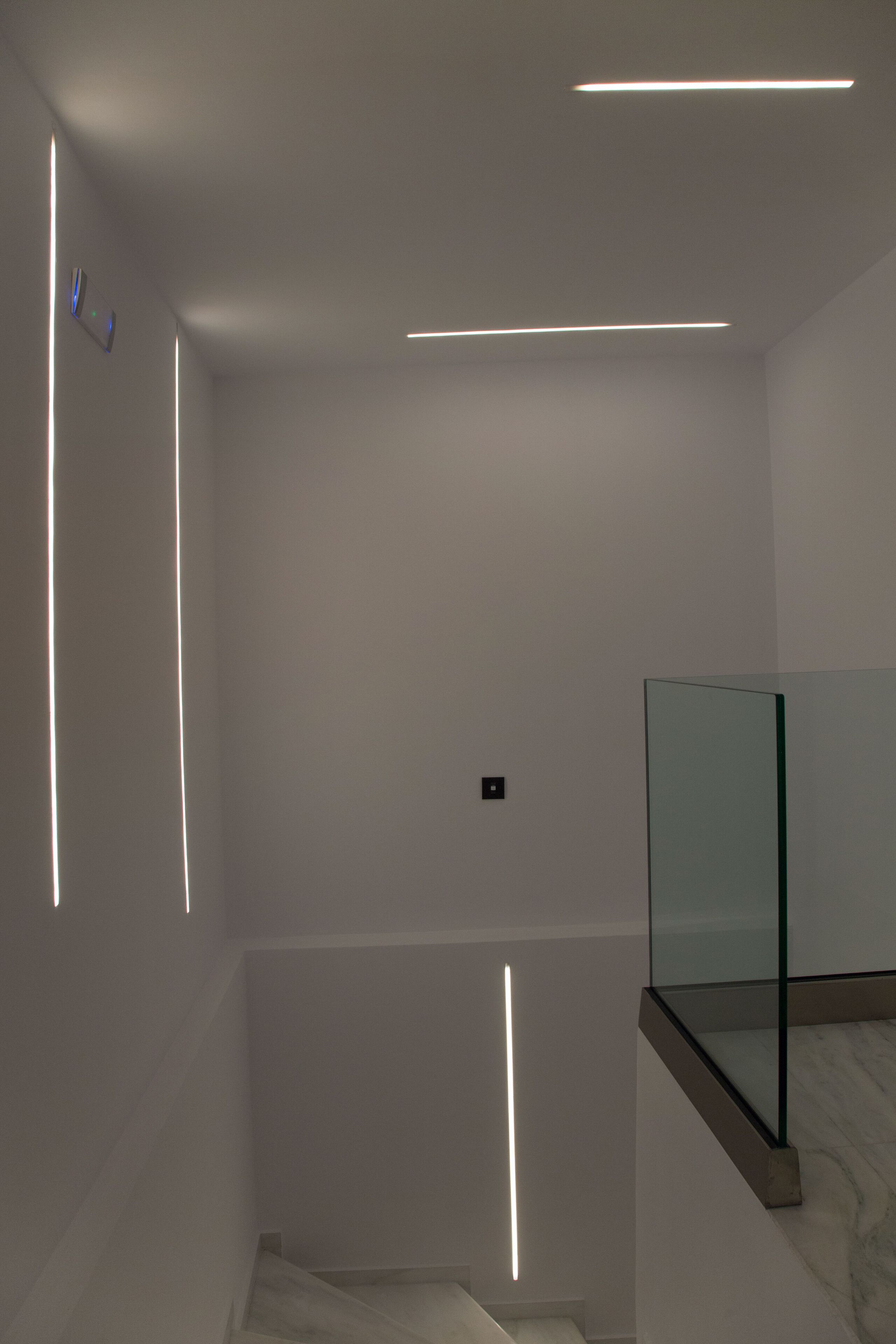 A modern bathroom with a glass shower enclosure, a marble floor, and recessed lighting.