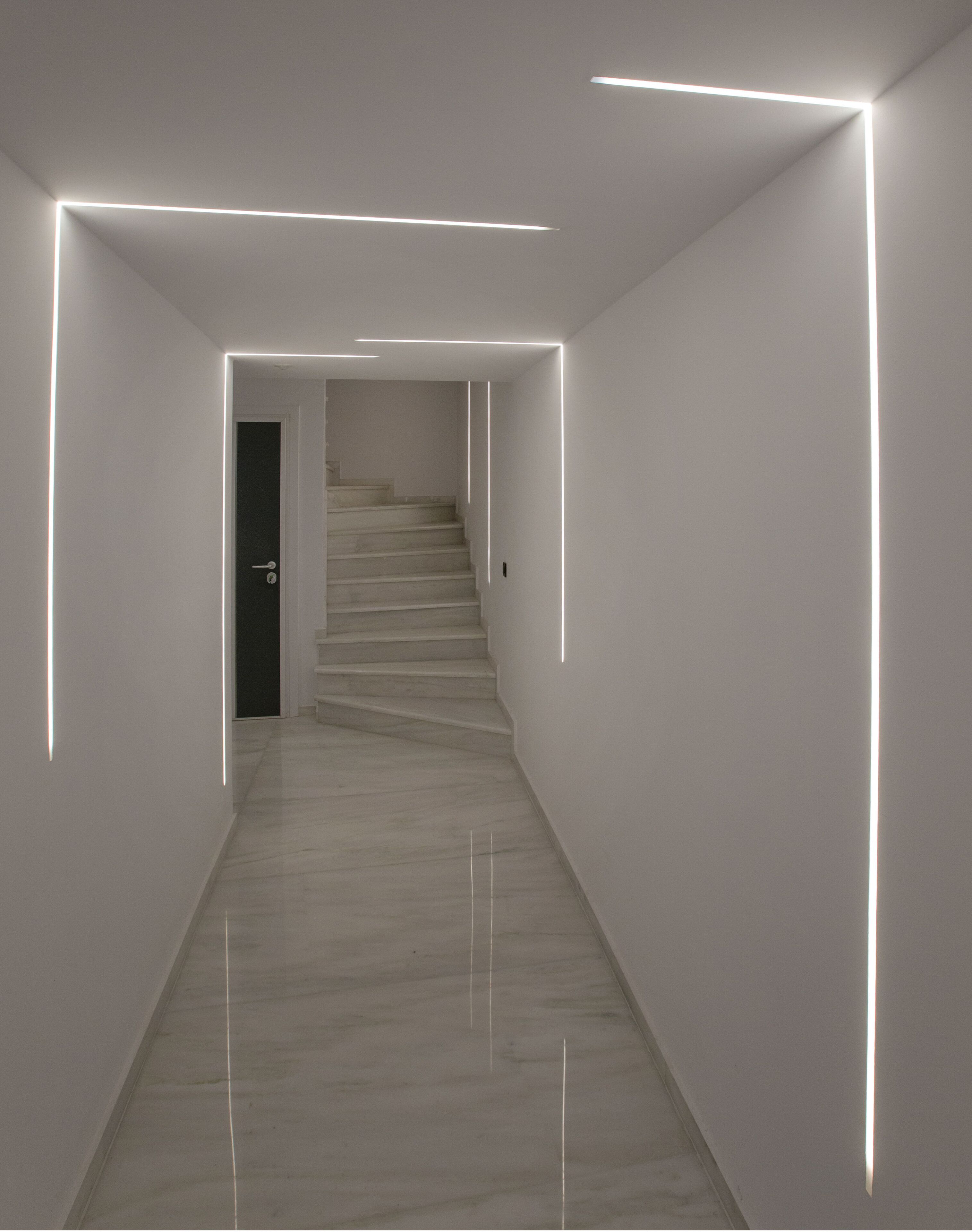 Un couloir moderne et minimaliste, doté d’un sol en marbre et de murs blancs.