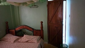 Un dormitorio con una cama de madera, una cesta verde y una puerta de madera.
