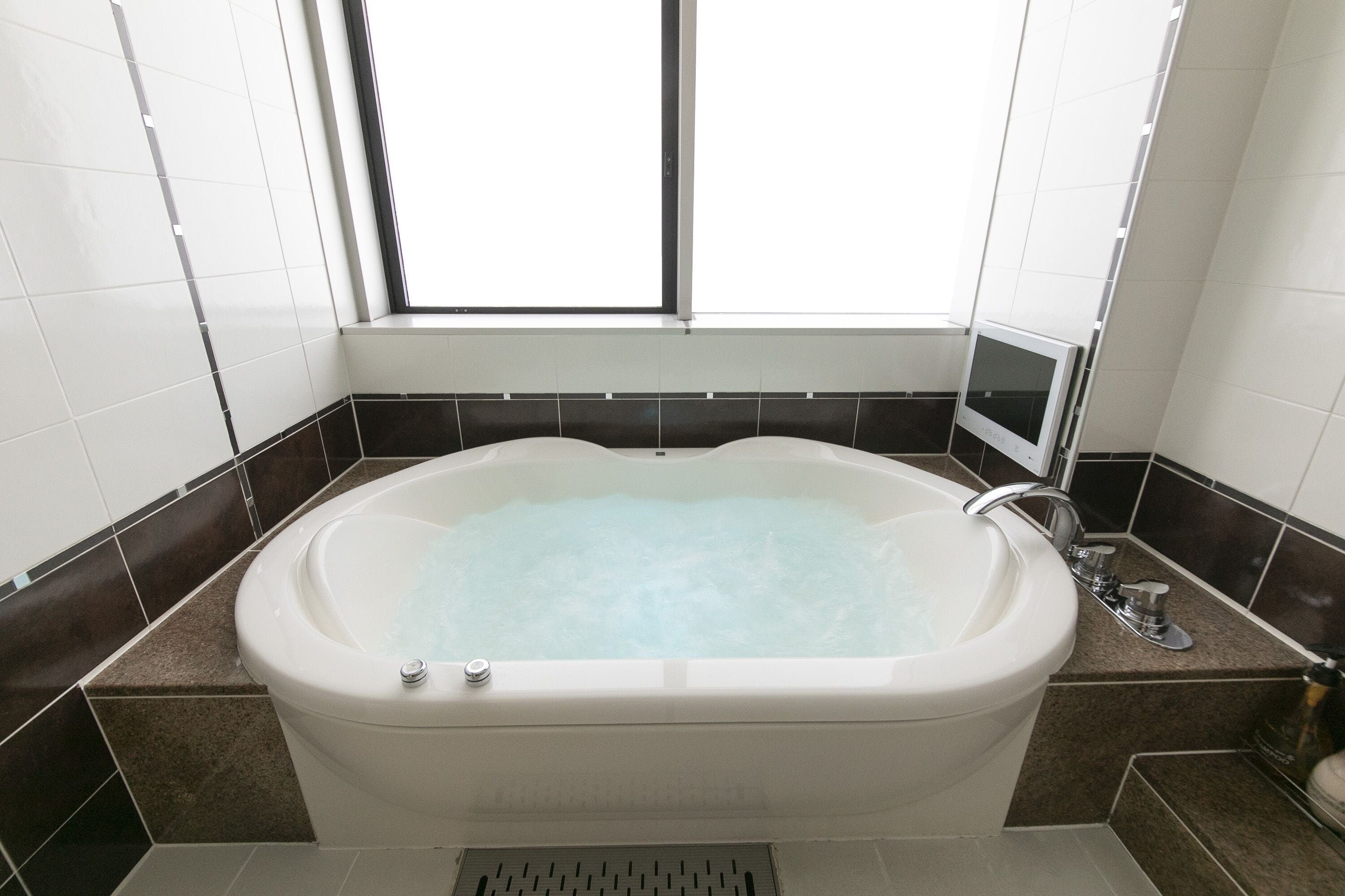 Une salle de bain moderne avec une baignoire sur pieds, une fenêtre et un miroir.