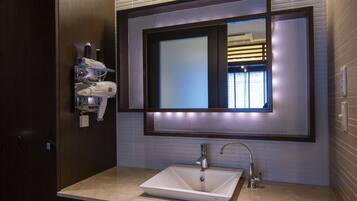 A modern bathroom with a large mirror, a white sink, and a hairdryer mounted on the wall.