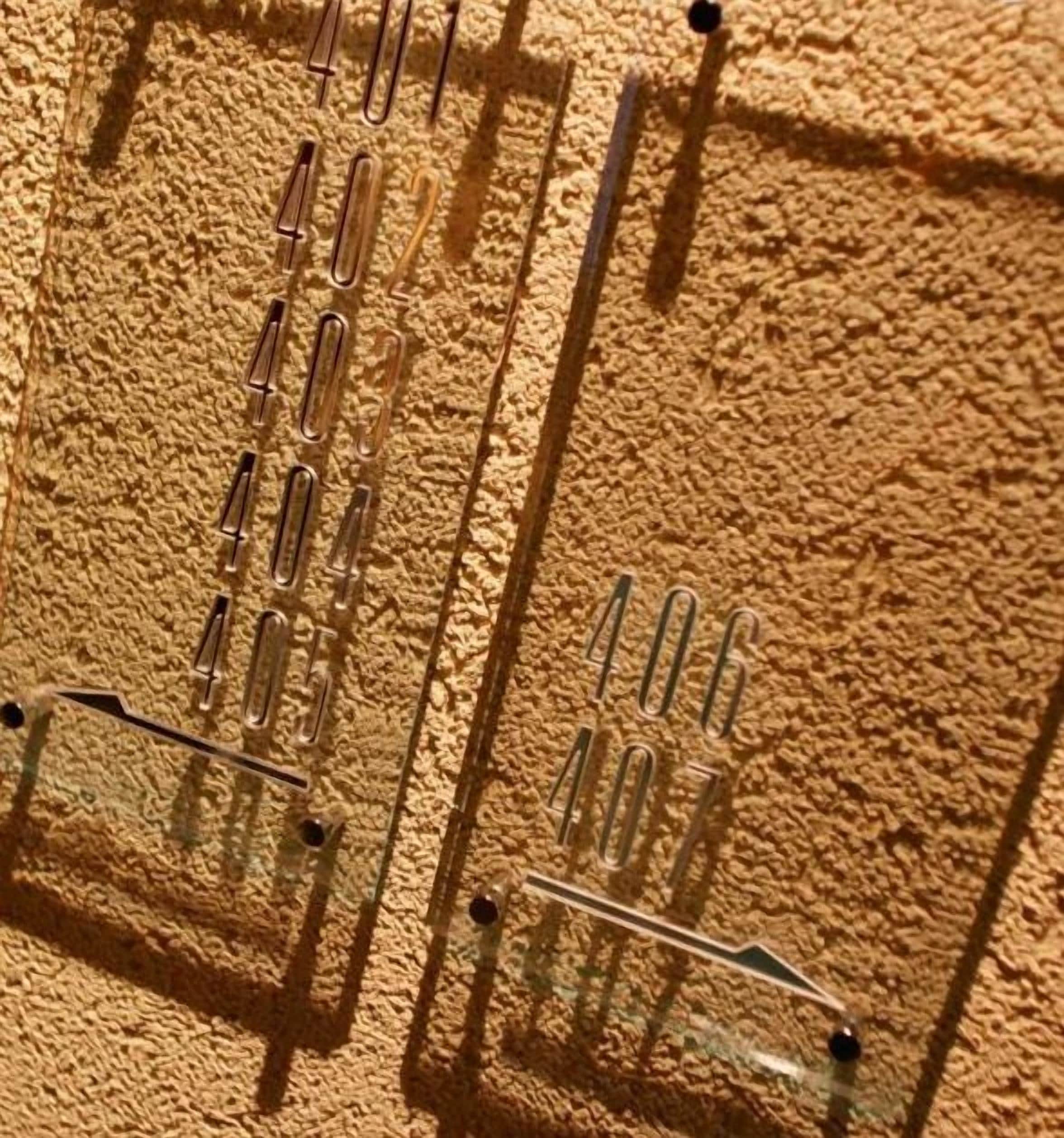 A close-up of a textured wall with a grid of metal brackets and a horizontal bar.